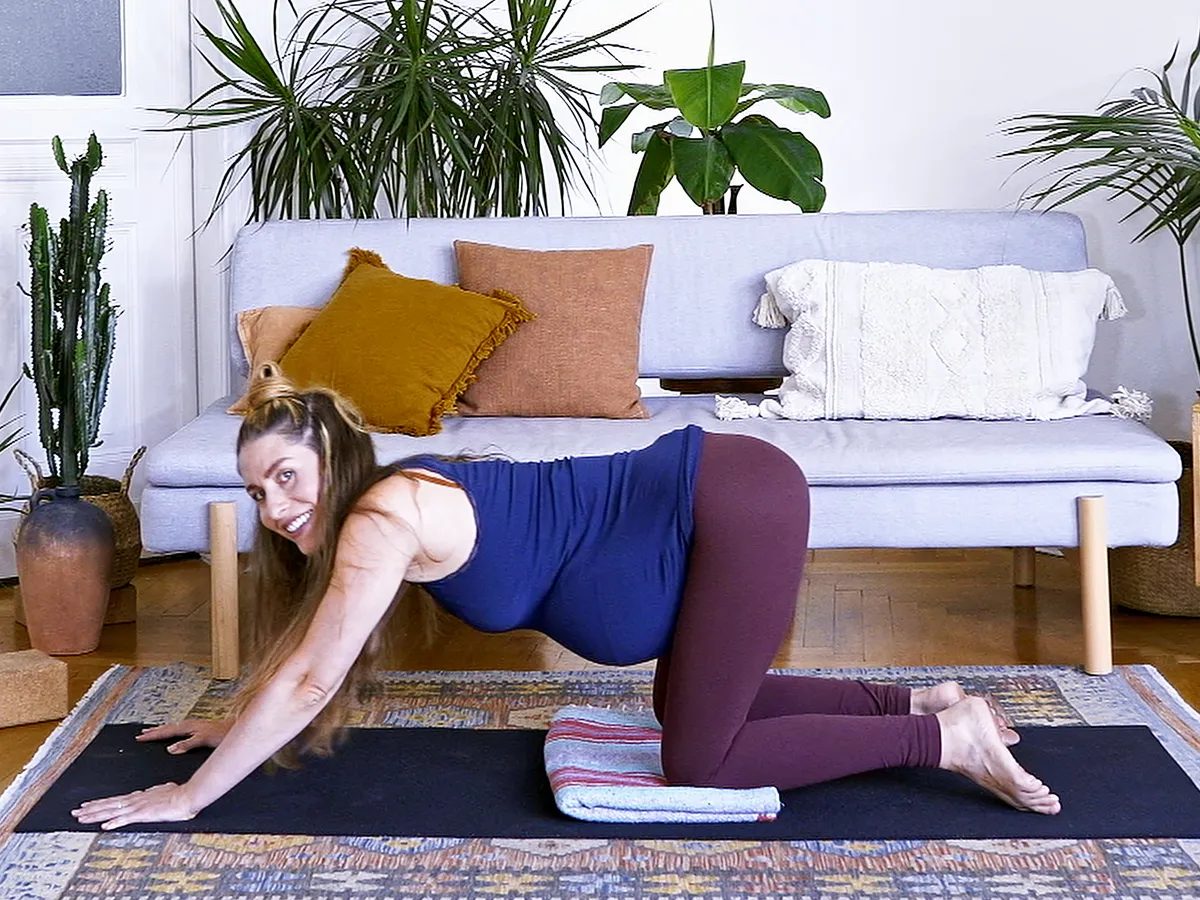 Jess Rose, pregnant, in a gentle cat-cow on her mat