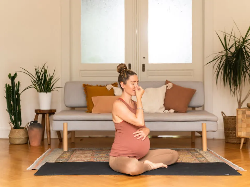 Jess Rose, pregnant, seated cross-legged doing a calming breathing practice