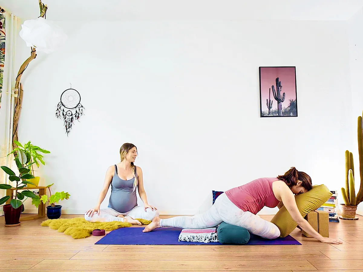 A pregnant student resting forward over a bolster while Jess Rose teaches a sleep class